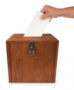 A man's hand putting an envelope in the slot of a box